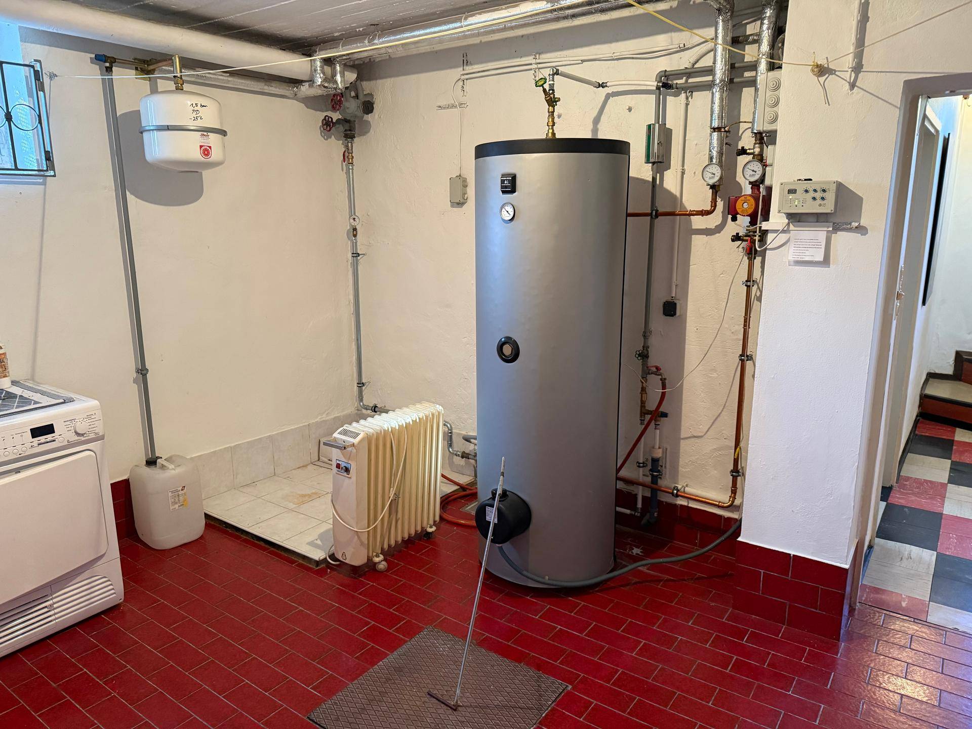 Hauswirtschaftsraum im Keller mit Warmwasserspeicher und Heizungsanlage, funktional eingerichtet.