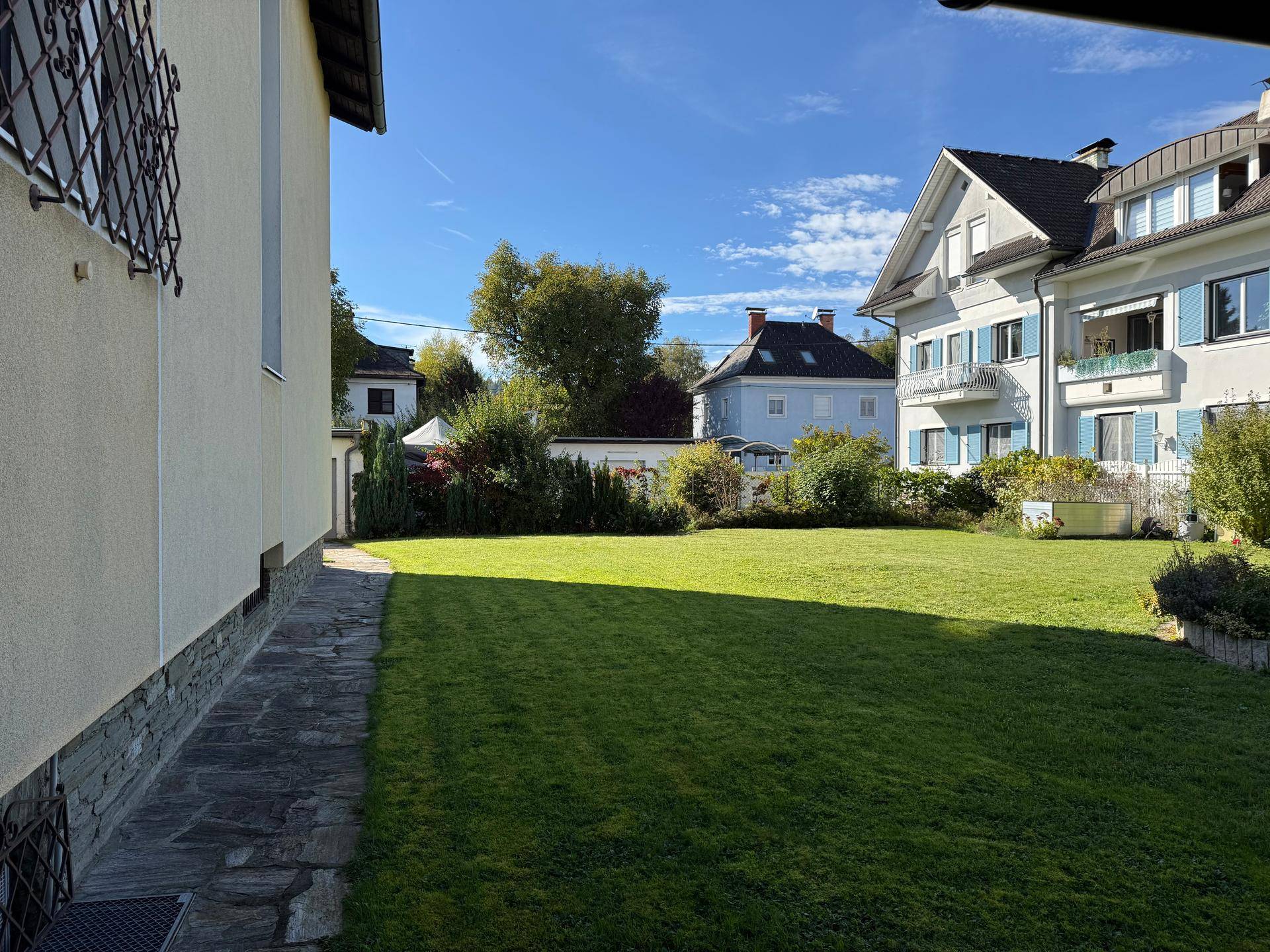 Weitläufige Rasenfläche im Garten neben dem Haus, umgeben von weiteren Wohnhäusern.