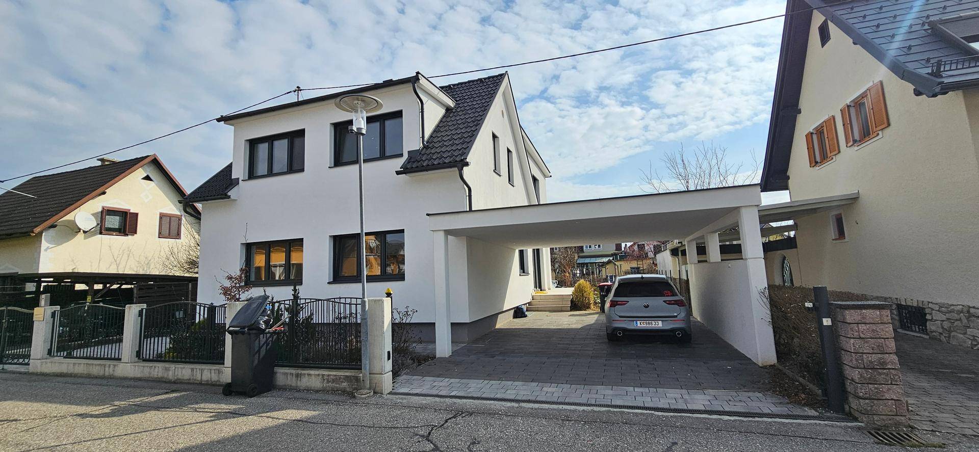 Vorderansicht des Hauses mit Carport und gepflasterter Zufahrt von der Straße.