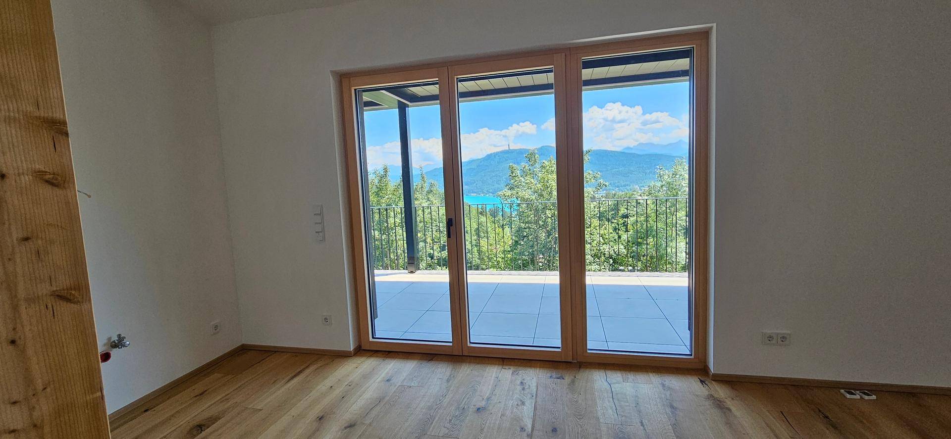 Heller Wohnraum mit Holzboden und großen Glasfronten, die einen weiten Seeblick bieten.