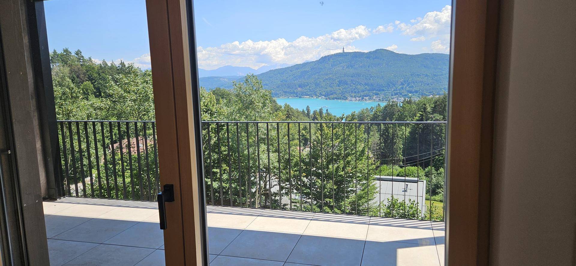 Geräumiger Balkon mit Fliesenboden und atemberaubendem Blick auf den See und die Berge.