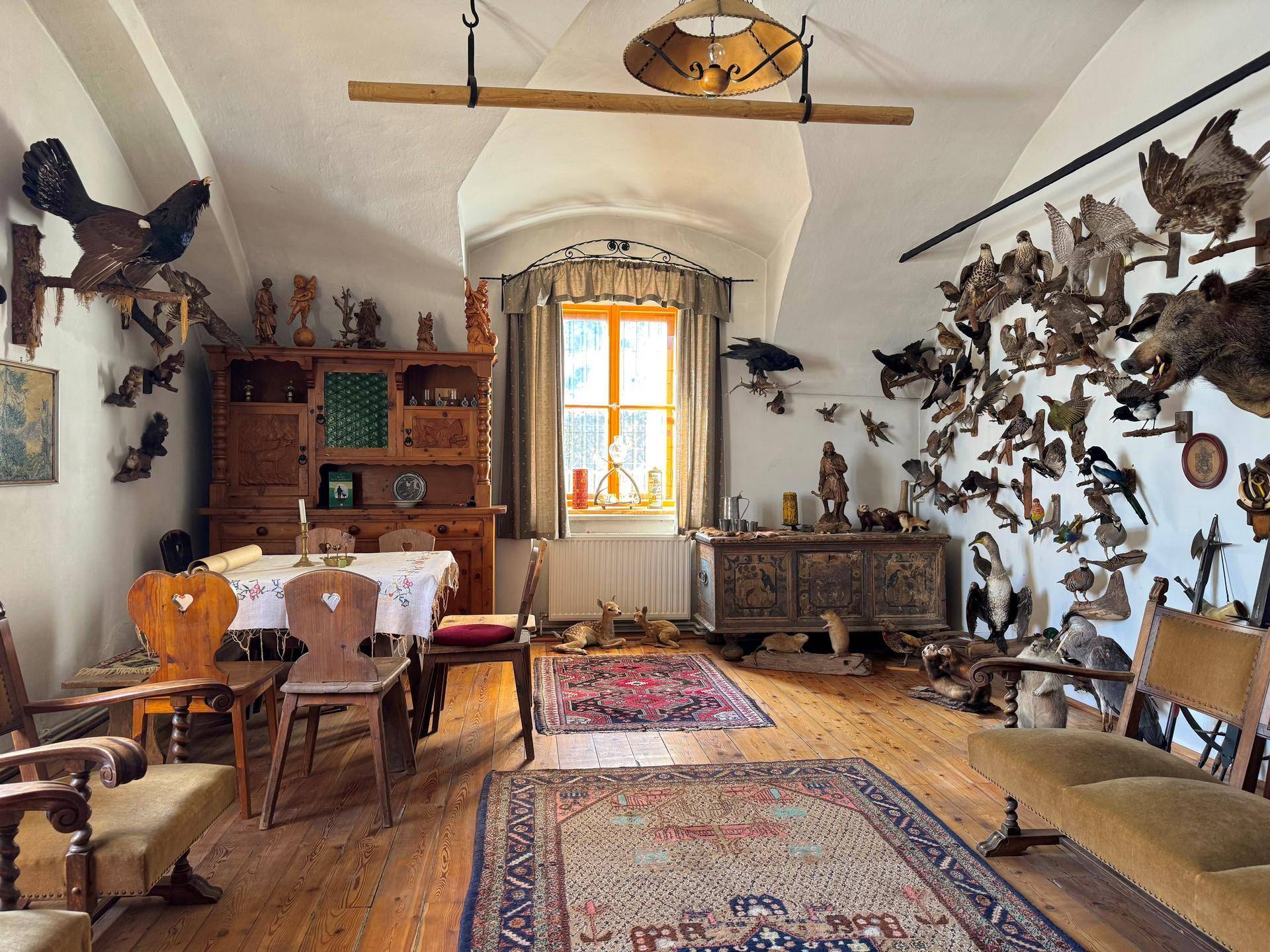 Rustikaler Essbereich mit Holzboden, Dachschräge und einer Sammlung von Jagdtrophäen.