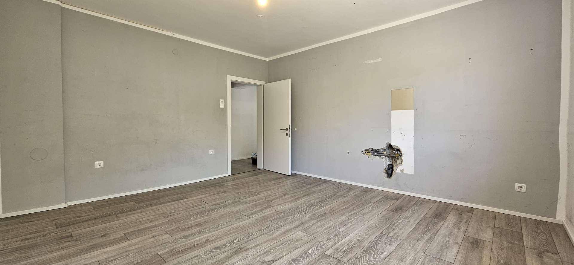 Schlafzimmer mit Laminatboden und grauen Wänden, bietet Potenzial für eine individuelle Renovierung.