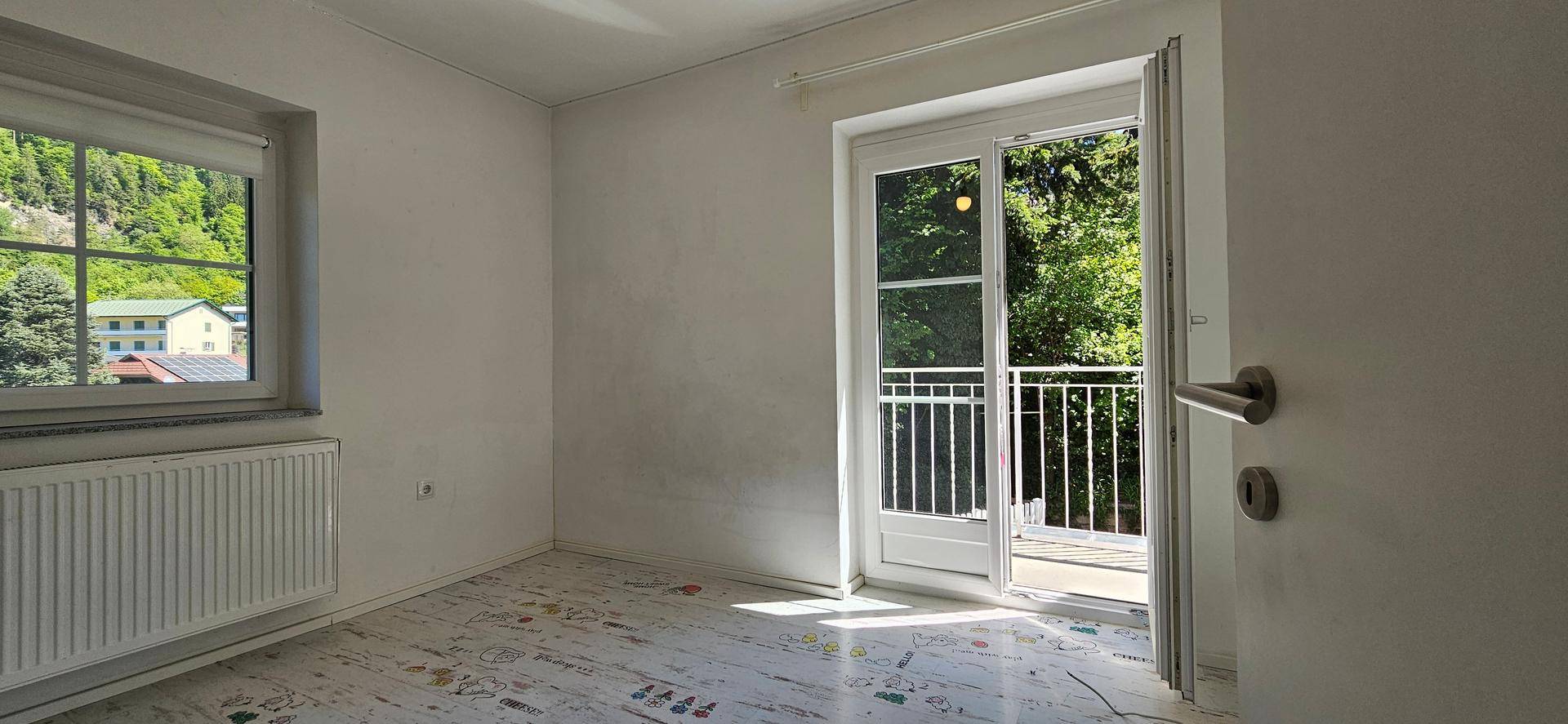 Helles Schlafzimmer mit Fenster und Zugang zu einem kleinen Balkon, ideal für frische Luft.
