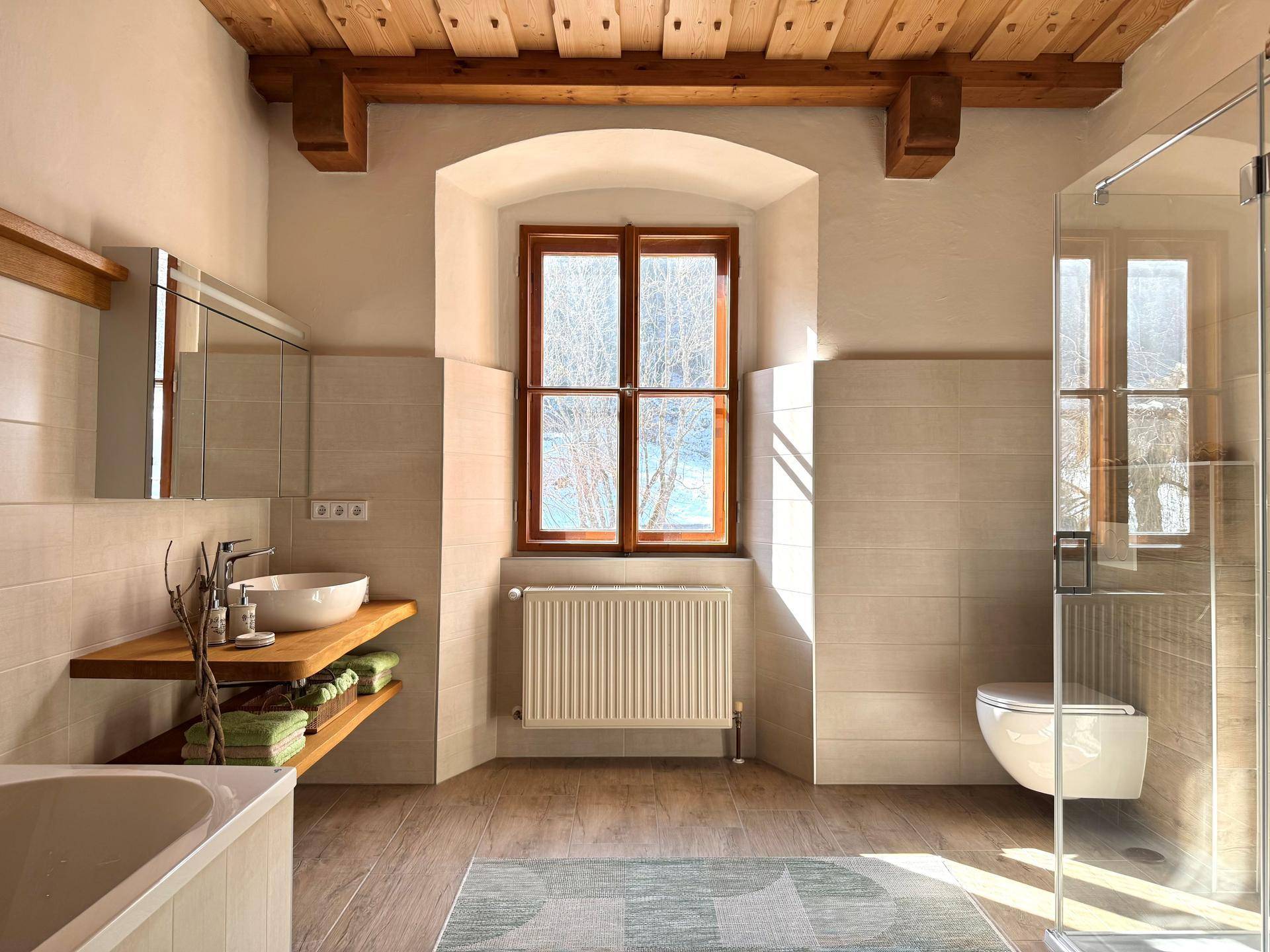 Modernisiertes Badezimmer mit Holzbalkendecke, begehbarer Dusche und Fenster.