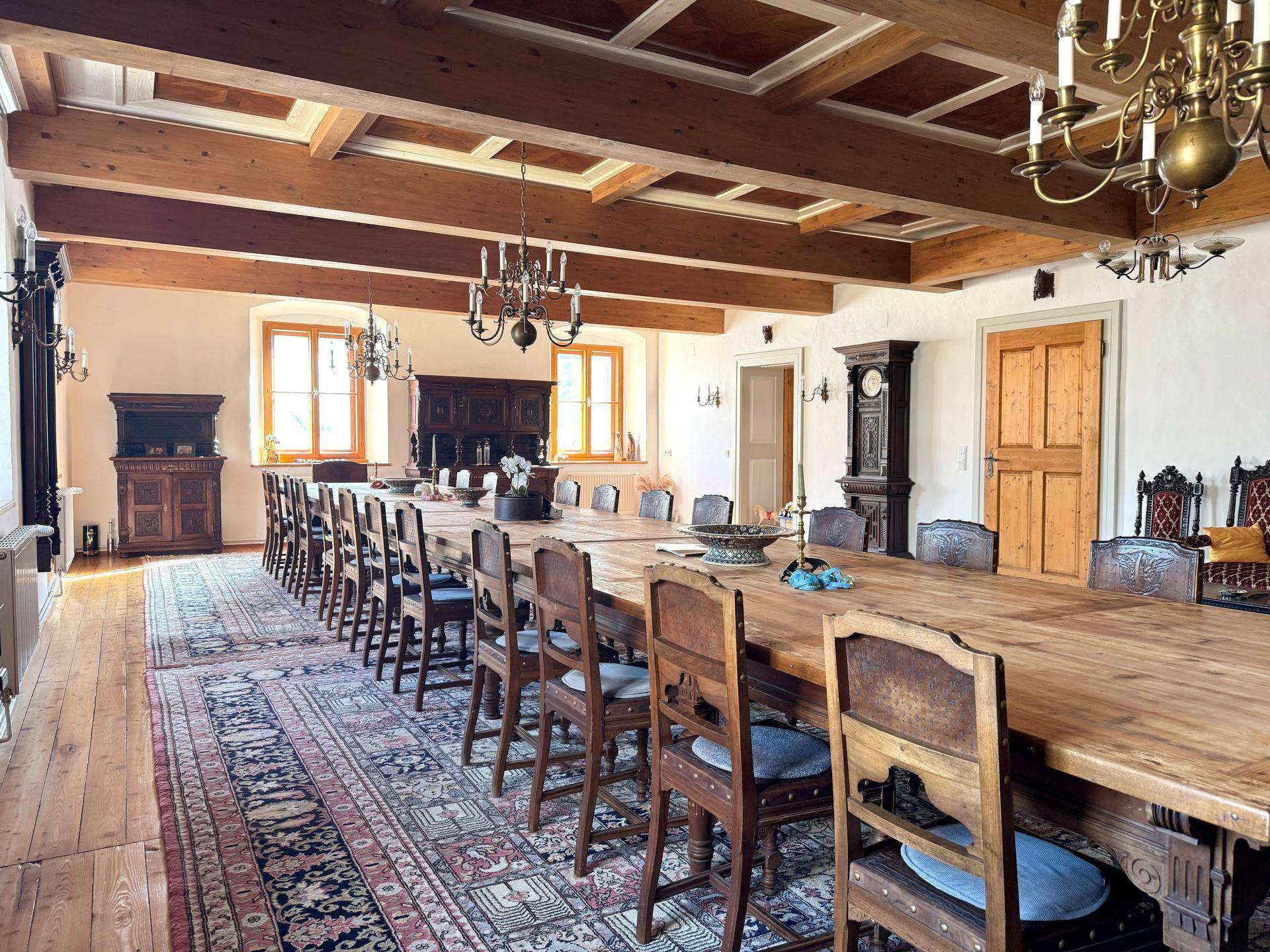 Großer Speisesaal mit rustikaler Holztafel, Holzbalkendecke und antiken Möbeln.