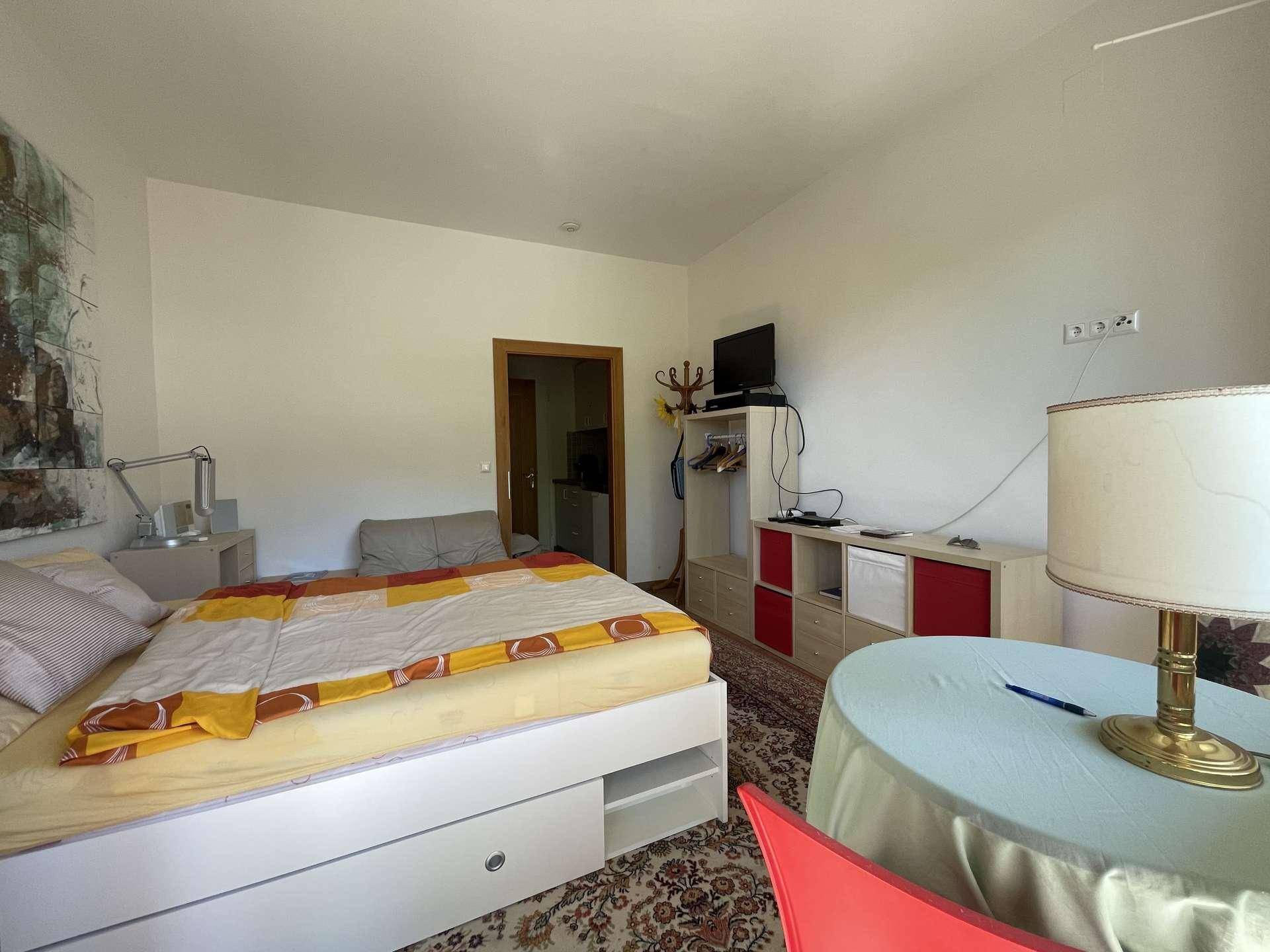 Gemütliches Schlafzimmer mit einem bequemen Bett, einem kleinen Tisch und einem Teppichboden.