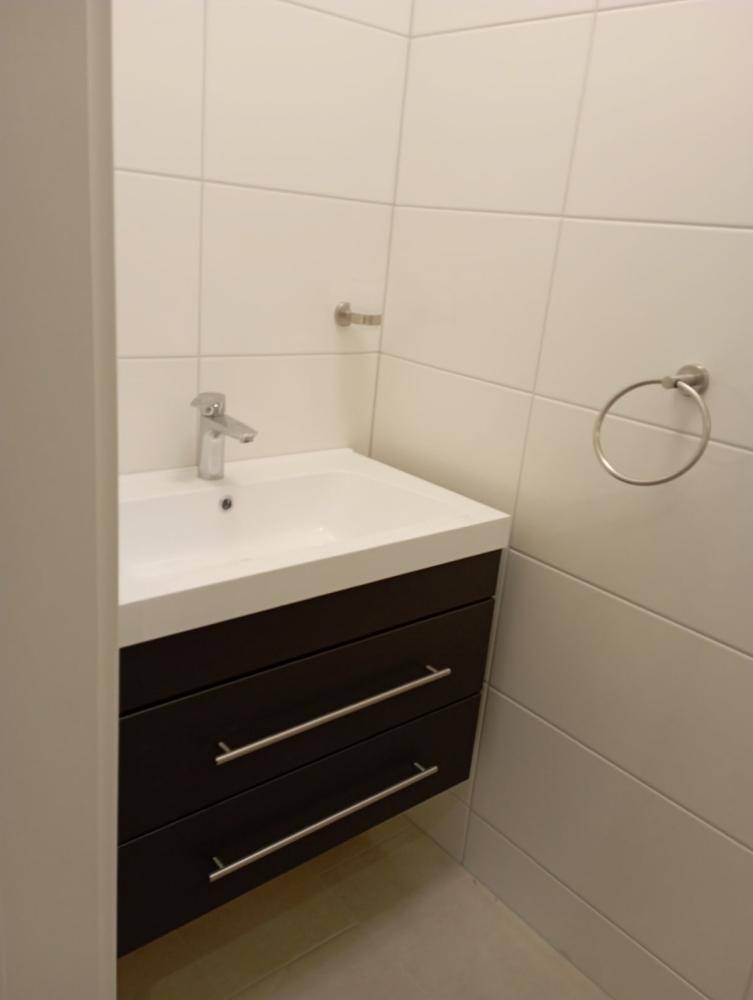 Modernes Badezimmer mit weiß gefliesten Wänden und einem Waschbeckenunterschrank.