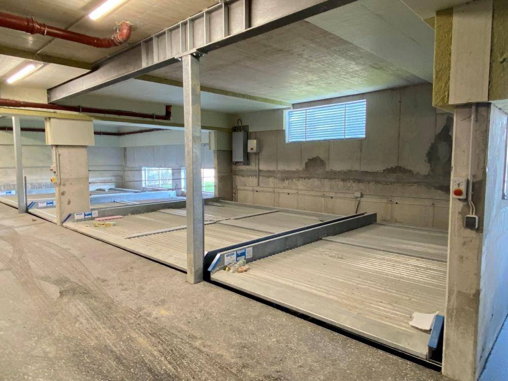 Tiefgarage mit modernen Parksystemen und Betonwänden, gut beleuchtet.