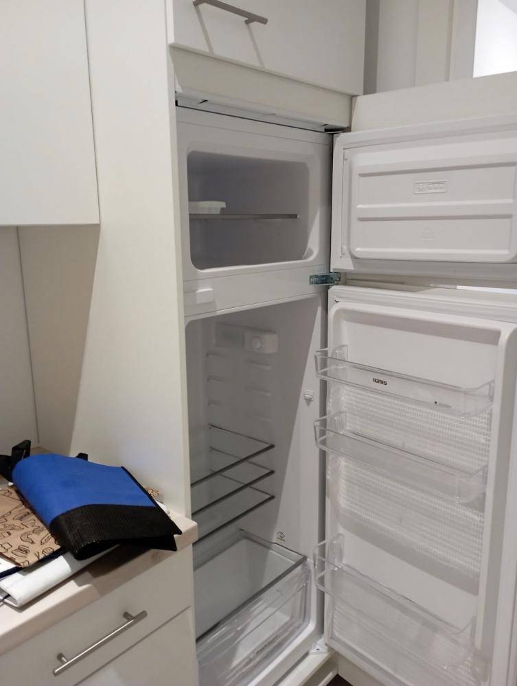 Integrierter Kühlschrank in einer modernen Küche mit weißen Schränken.