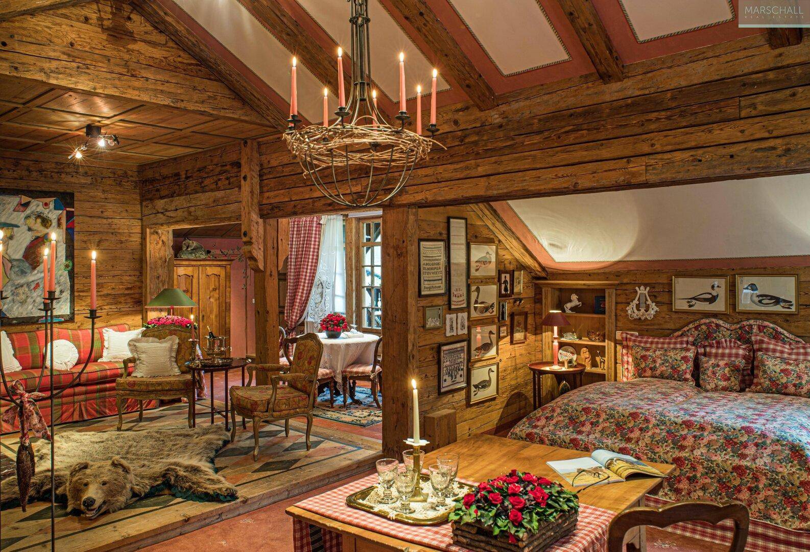 Gemütliches Wohnzimmer im alpinen Stil mit Holzbalken, Kamin und traditionellen Möbeln.