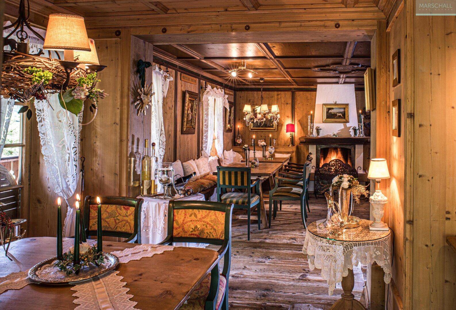 Rustikaler Essbereich mit Holztischen, Bänken und einem Kamin, ideal für gesellige Runden.