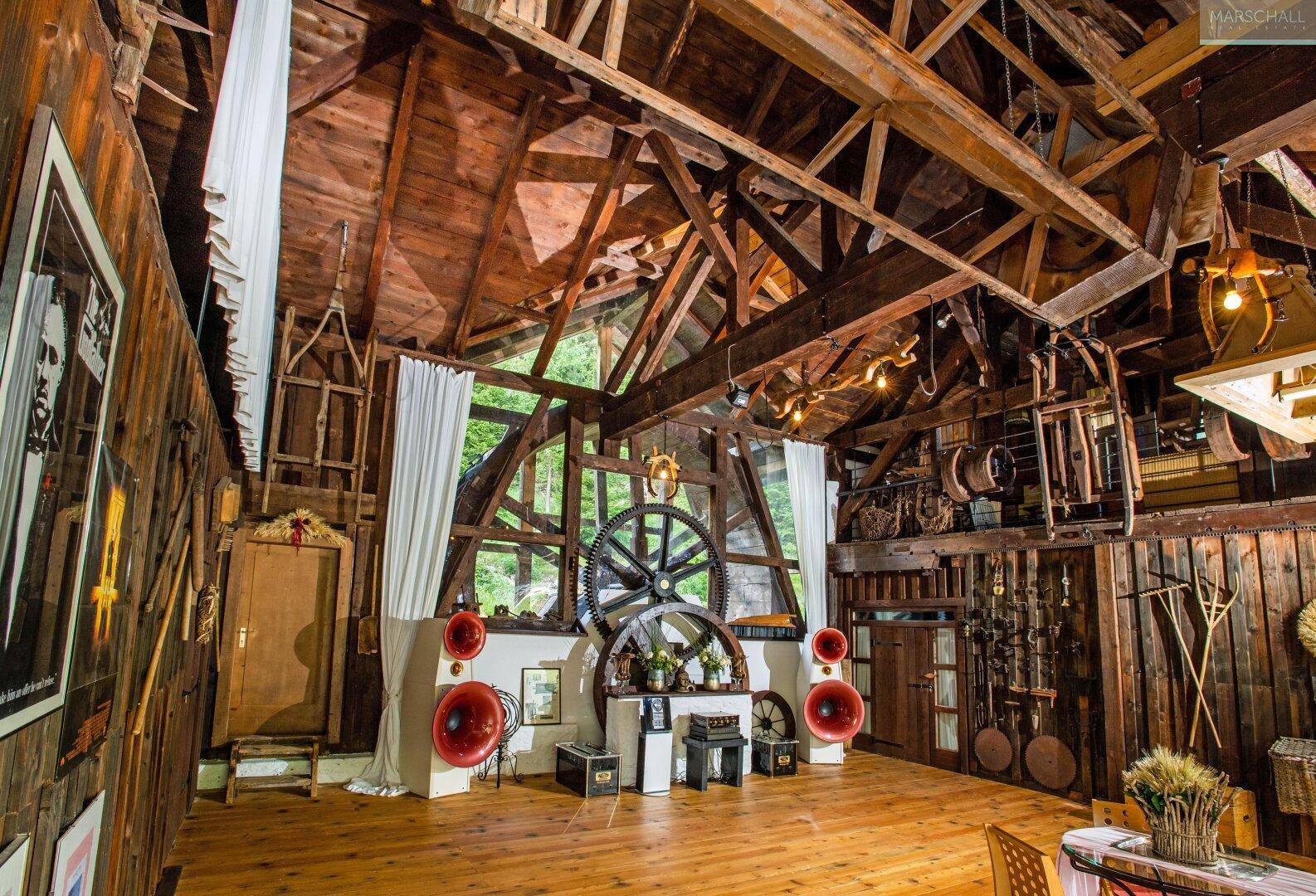 Großer Raum mit hoher Holzdecke und rustikalen Dekorationen, möglicherweise ein Veranstaltungsbereich.