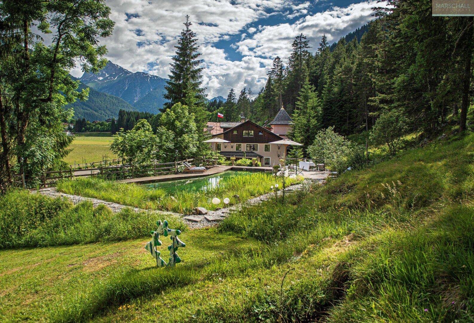 Weitläufiges Anwesen mit großem Garten, Schwimmteich und Bergblick, umgeben von Natur.