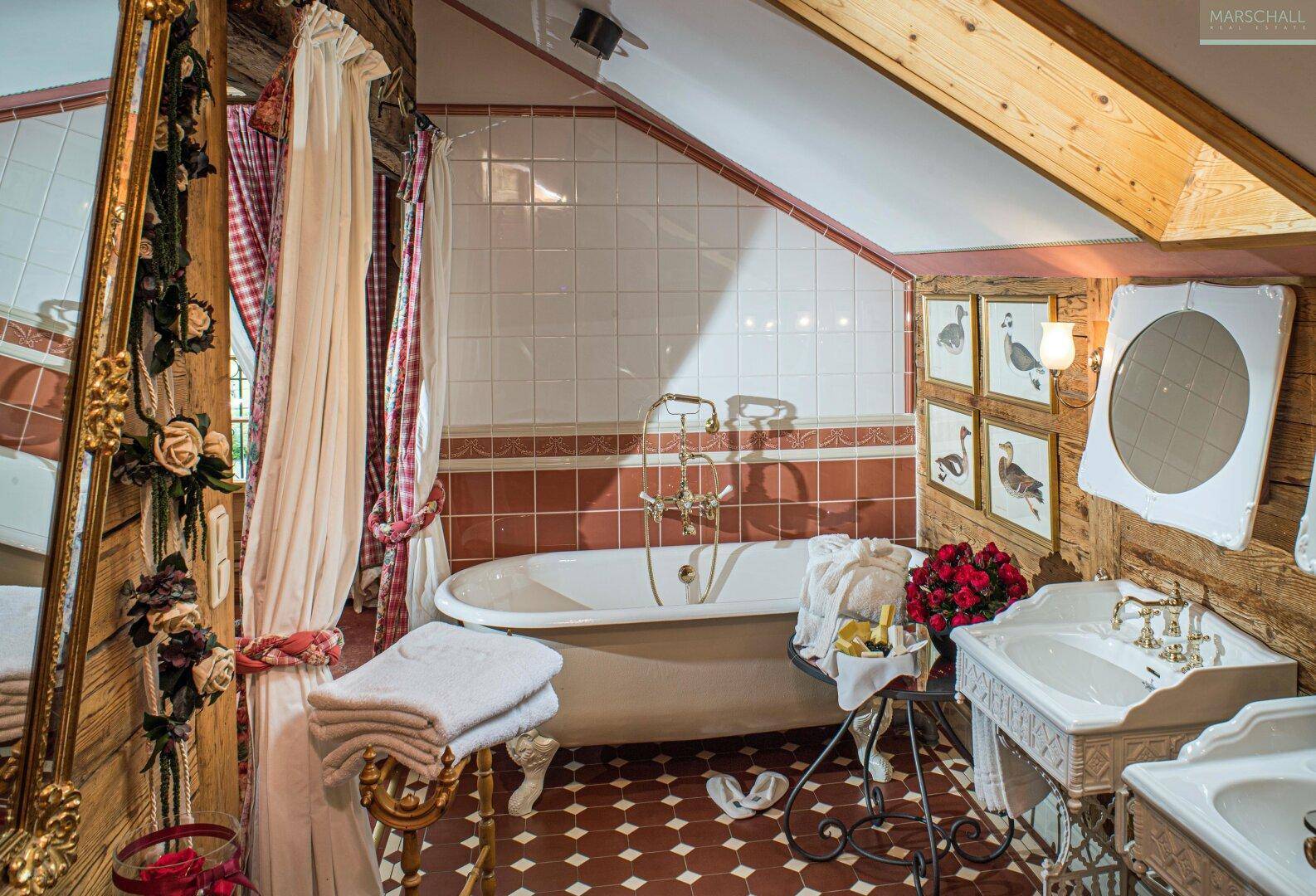 Charmantes Badezimmer im Dachgeschoss mit freistehender Badewanne, zwei Waschbecken und rustikalen Fliesen.