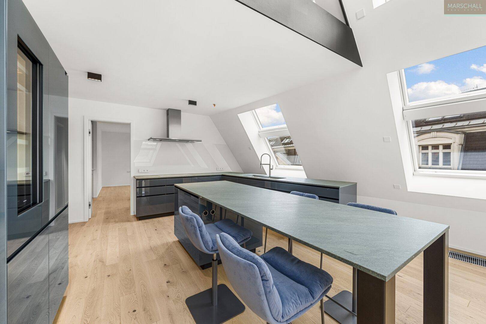 Moderne Küche mit grauen Schränken, Essbereich und Dachfenstern für viel Tageslicht.