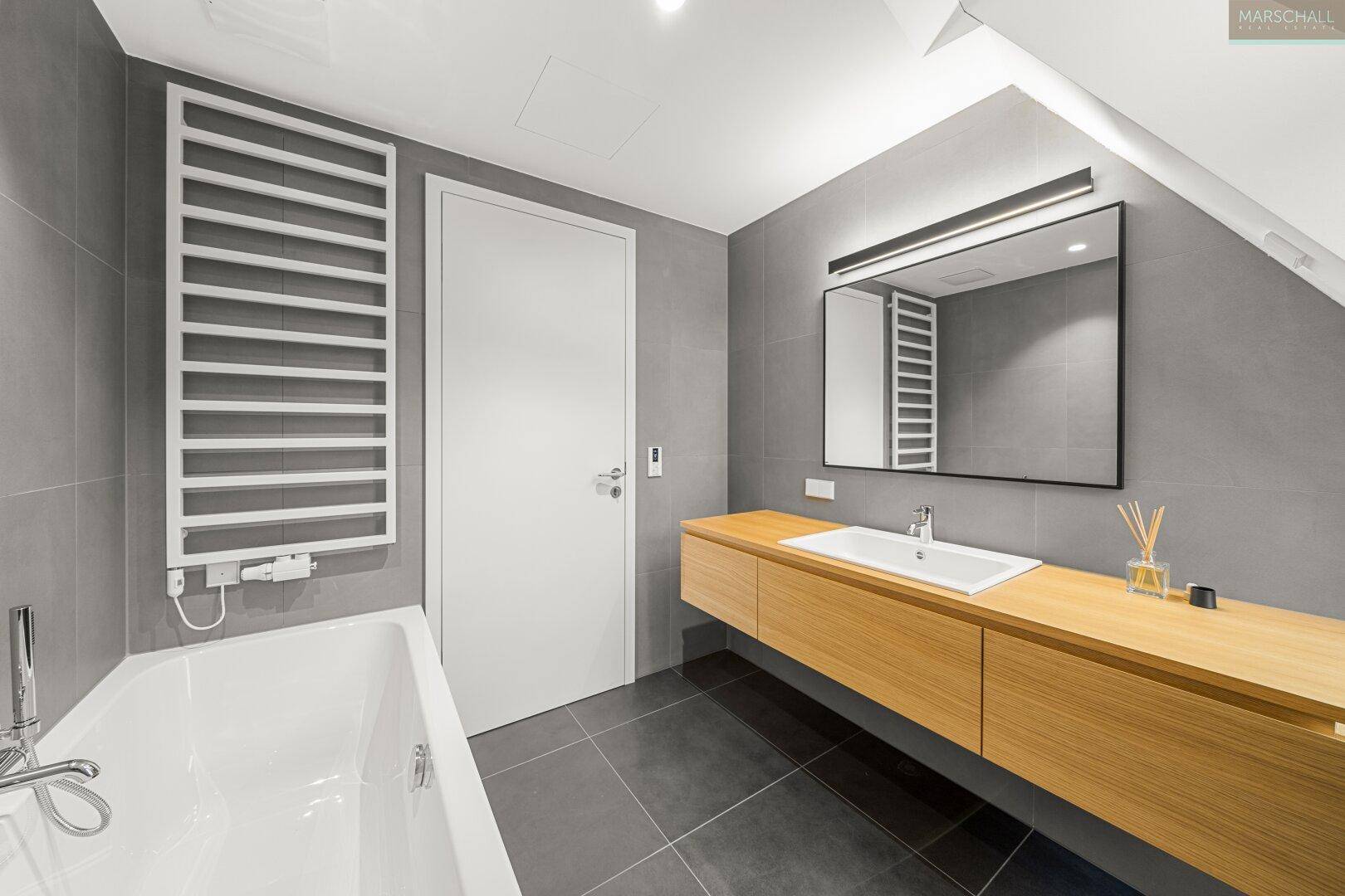 Modernes Badezimmer mit Badewanne, Einzelwaschbecken und beheiztem Handtuchhalter.