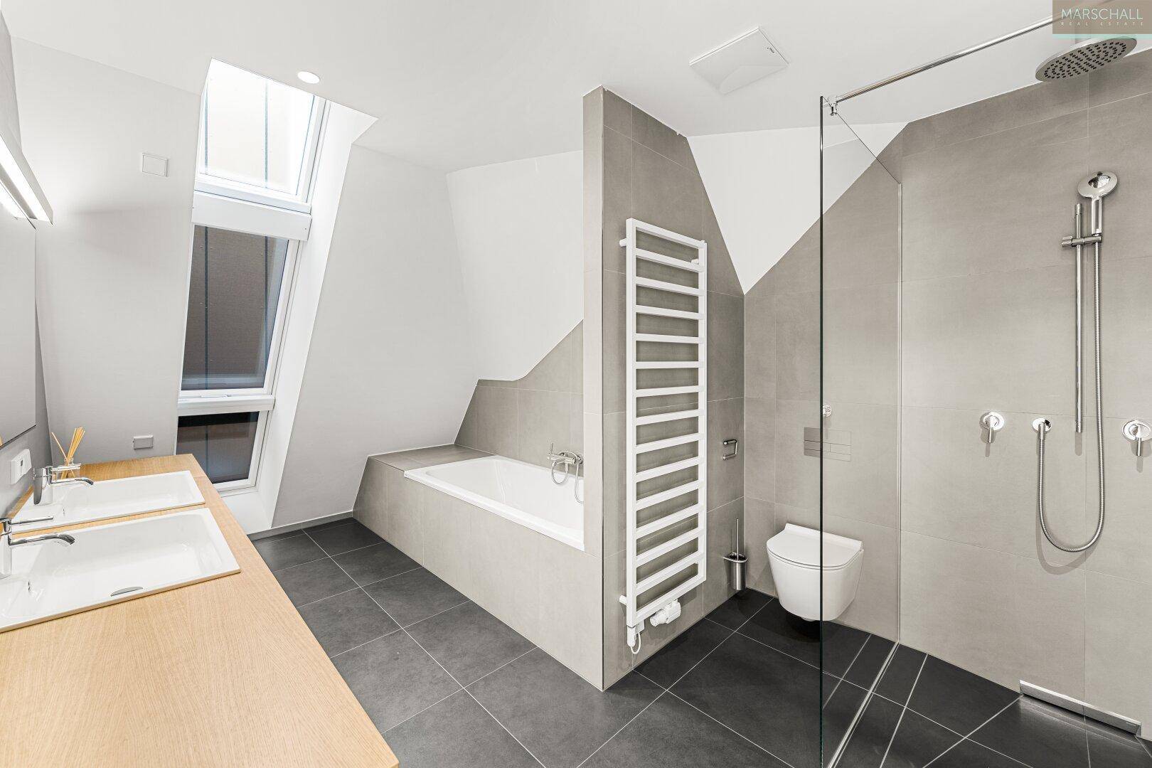 Modernes Badezimmer mit Doppelwaschbecken, Badewanne, Dusche und Dachfenster.