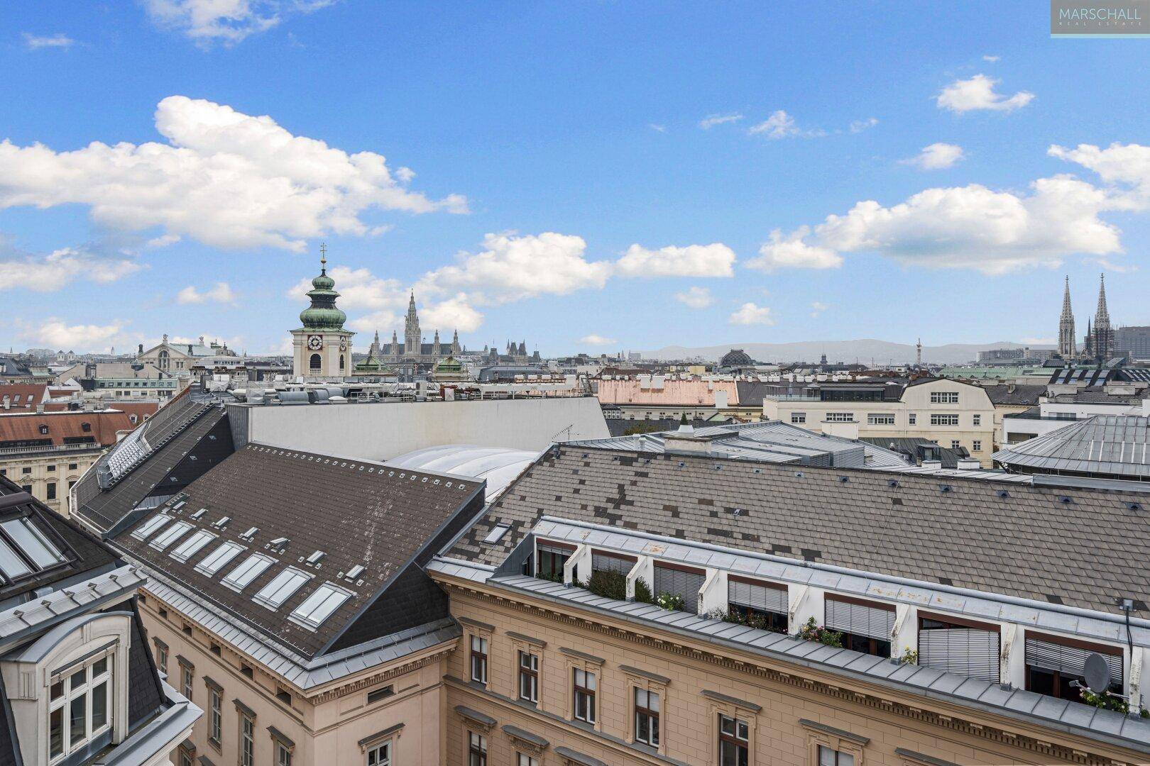 Weitläufiger Blick über die Dächer der Stadt mit historischen Gebäuden und Kirchtürmen.