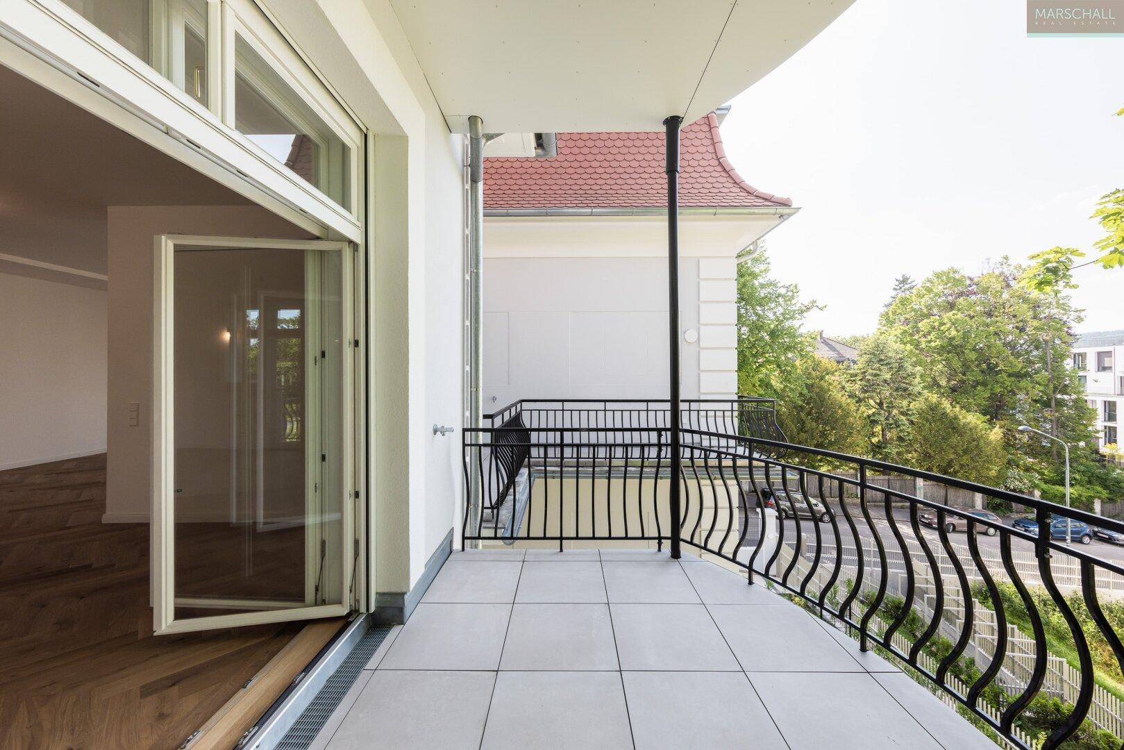 Geräumiger Balkon mit Fliesenboden und schmiedeeisernem Geländer, mit Blick auf die Umgebung.