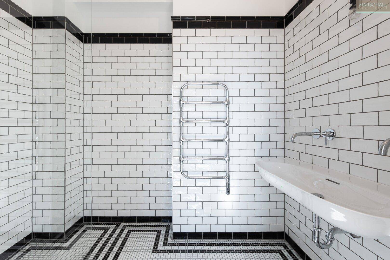 Modernes Badezimmer mit weißen U-Bahn-Fliesen, schwarzem Akzent und stilvollem Mosaikboden.