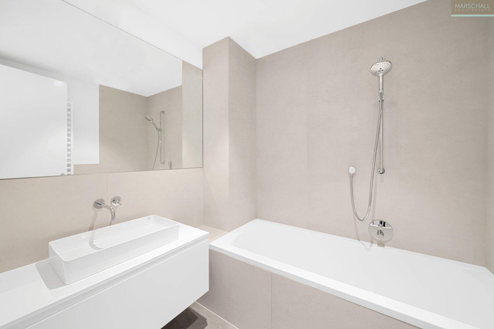 Modernes Badezimmer mit Badewanne, Einzelwaschbecken und großem Spiegel.