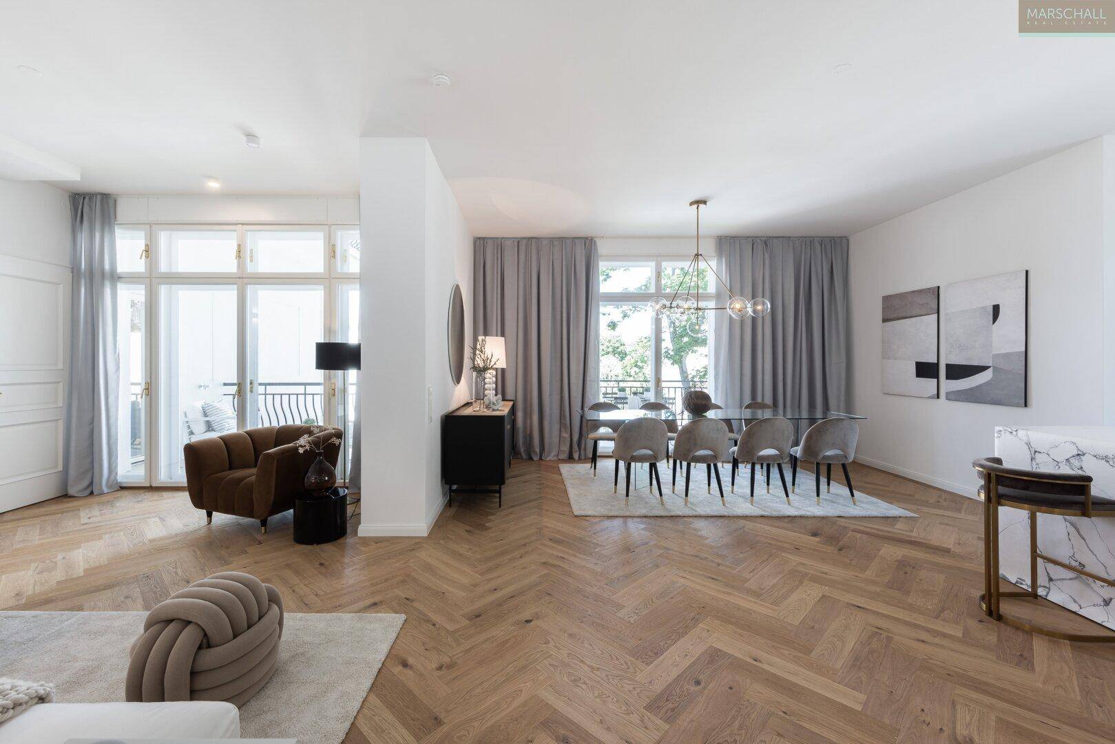 Eleganter Wohn- und Essbereich mit Fischgrätparkett, großen Fenstern und Zugang zu einem französischen Balkon.