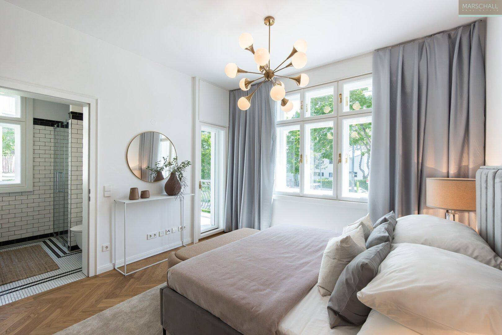 Helles Schlafzimmer mit Parkettboden, modernem Lichtdesign und direktem Zugang zum stilvollen Badezimmer.