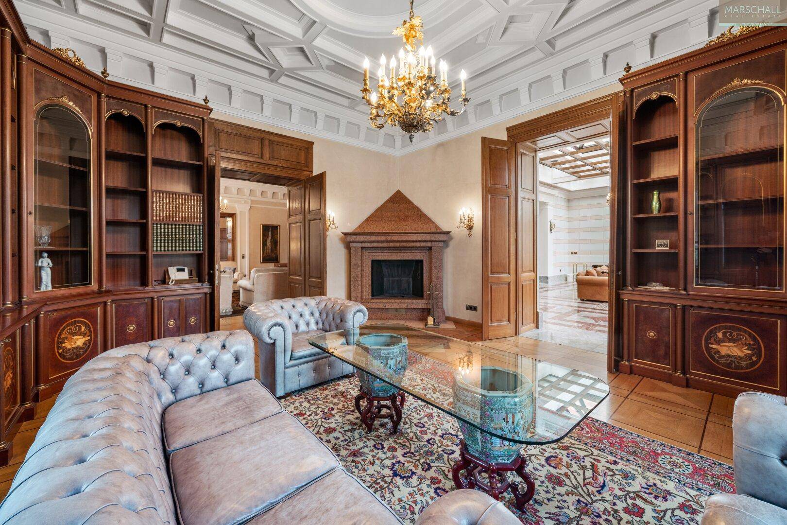 Gemütliche Bibliothek mit Kamin, eingebauten Holzregalen und eleganten Sitzmöbeln für entspannte Stunden.