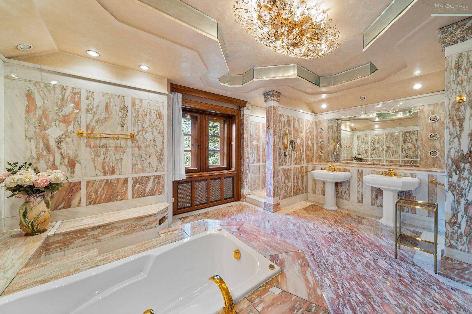 Luxuriöses Badezimmer mit Marmorverkleidung, Doppelwaschbecken und großer Badewanne.