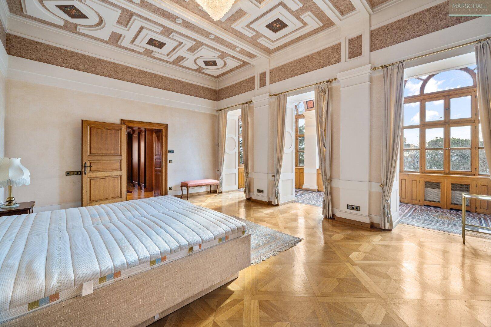Helles Schlafzimmer mit elegantem Parkettboden, hohen Decken und großen Fenstern für viel Licht.