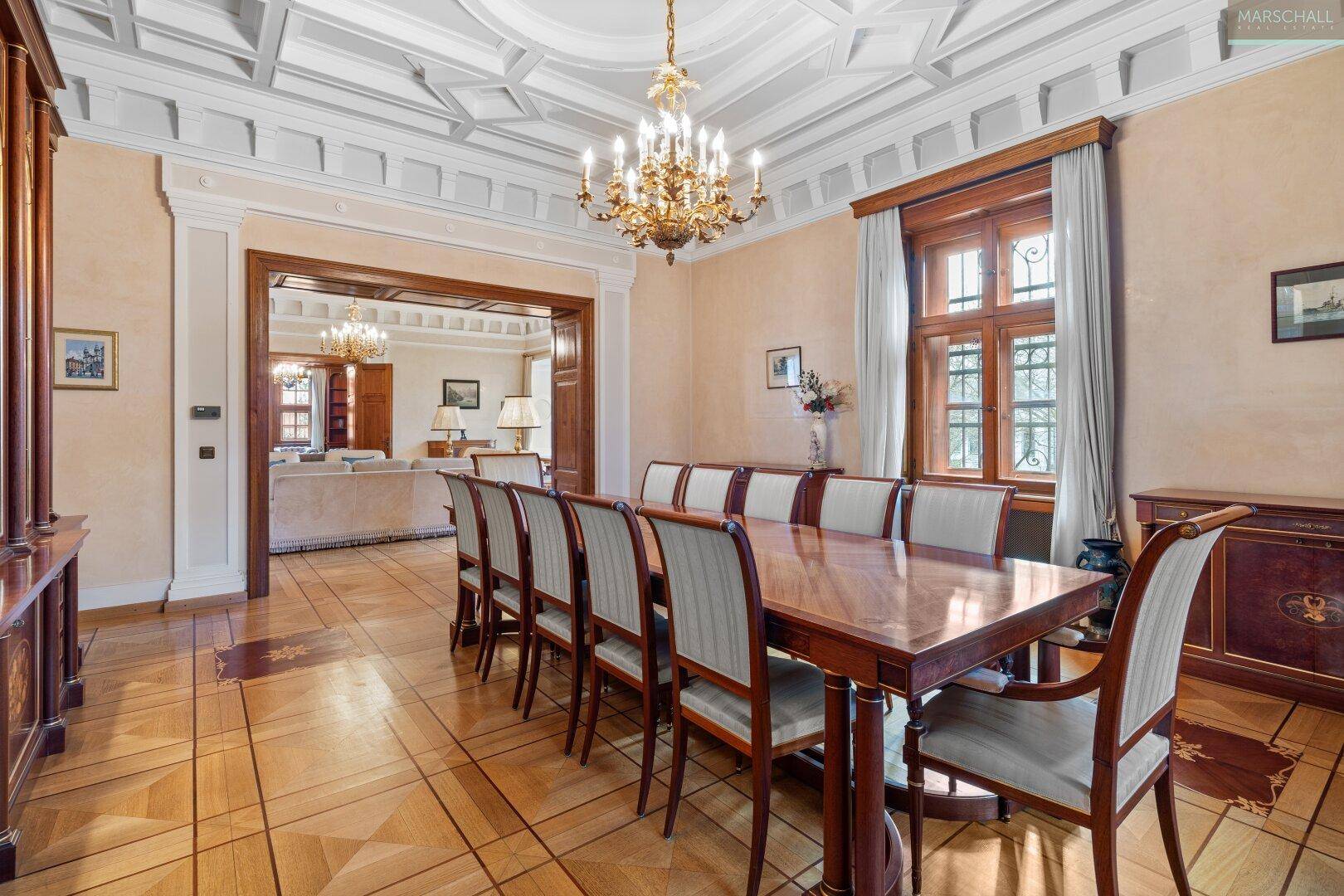 Eleganter Speisesaal mit großem Holztisch, passenden Stühlen und Blick in den Wohnbereich.