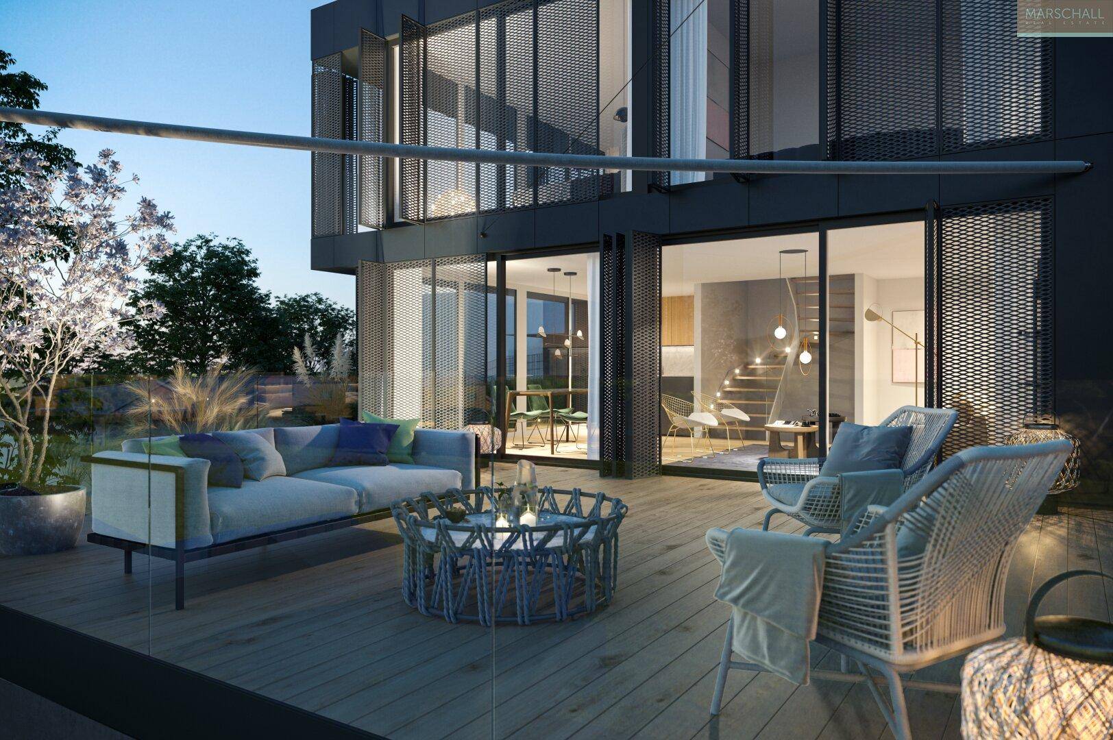 Gemütliche Terrasse am Abend mit stilvollen Lounge-Möbeln und Blick in den beleuchteten Wohnbereich.