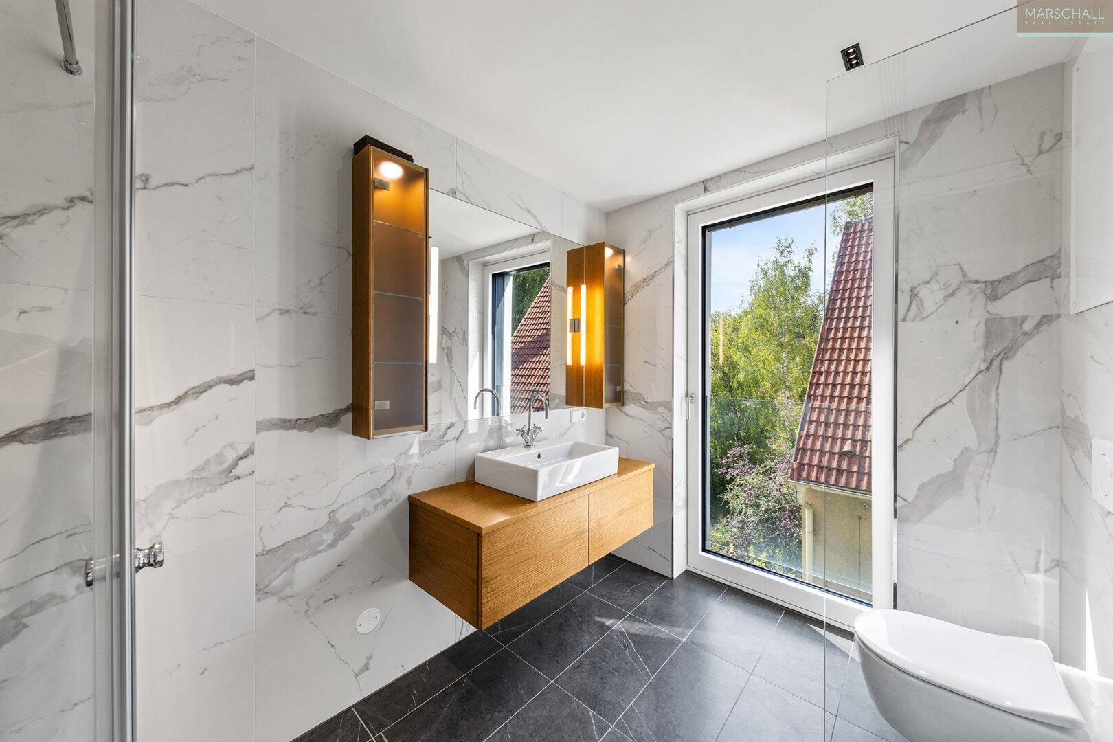 Modernes Badezimmer mit Marmorfliesen, Duschkabine, Einzelwaschbecken und Fenster mit Ausblick.