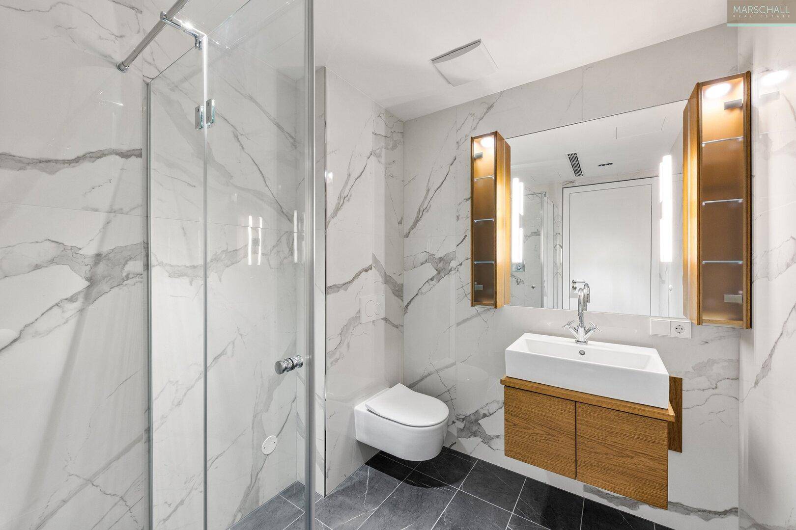 Modernes Badezimmer mit Marmorfliesen, Duschkabine, Einzelwaschbecken und Wand-WC.