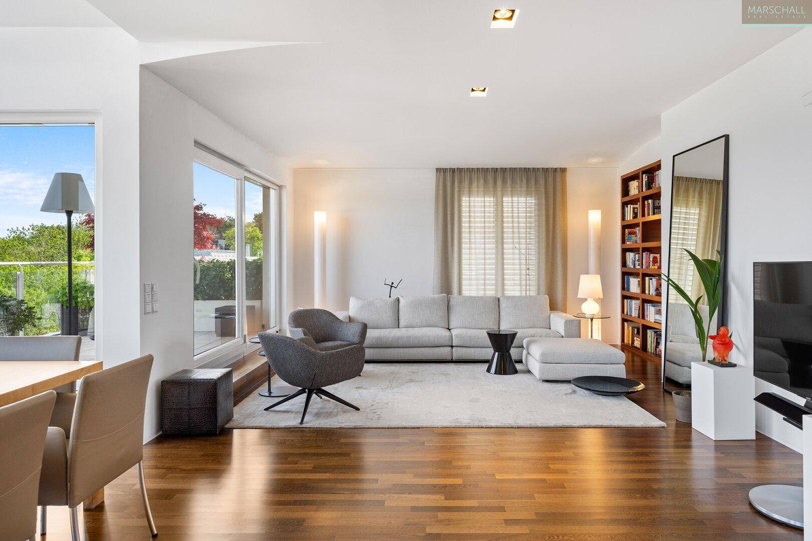Gemütliches Wohnzimmer mit hellem Sofa, Holzboden und großem Bücherregal an der Wand.