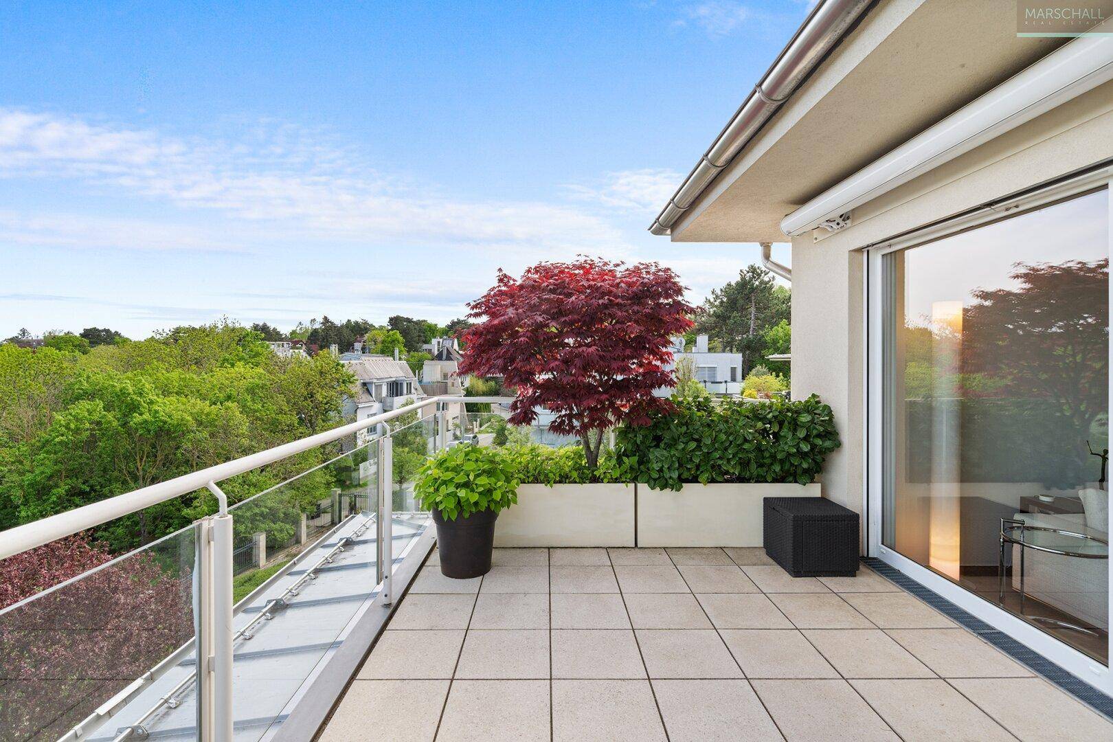 Heller Balkon mit Fliesenboden, Glasgeländer und Pflanzen, bietet einen schönen Ausblick.