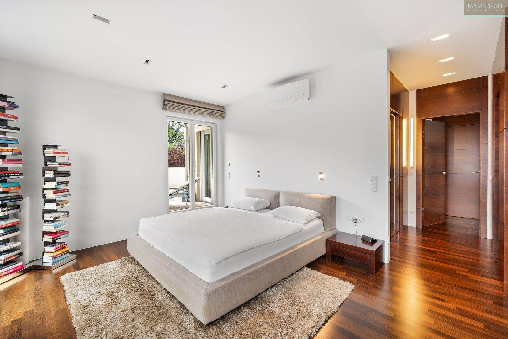 Schlafzimmer mit Doppelbett, Holzboden, Klimaanlage und Zugang zu einem Außenbereich.