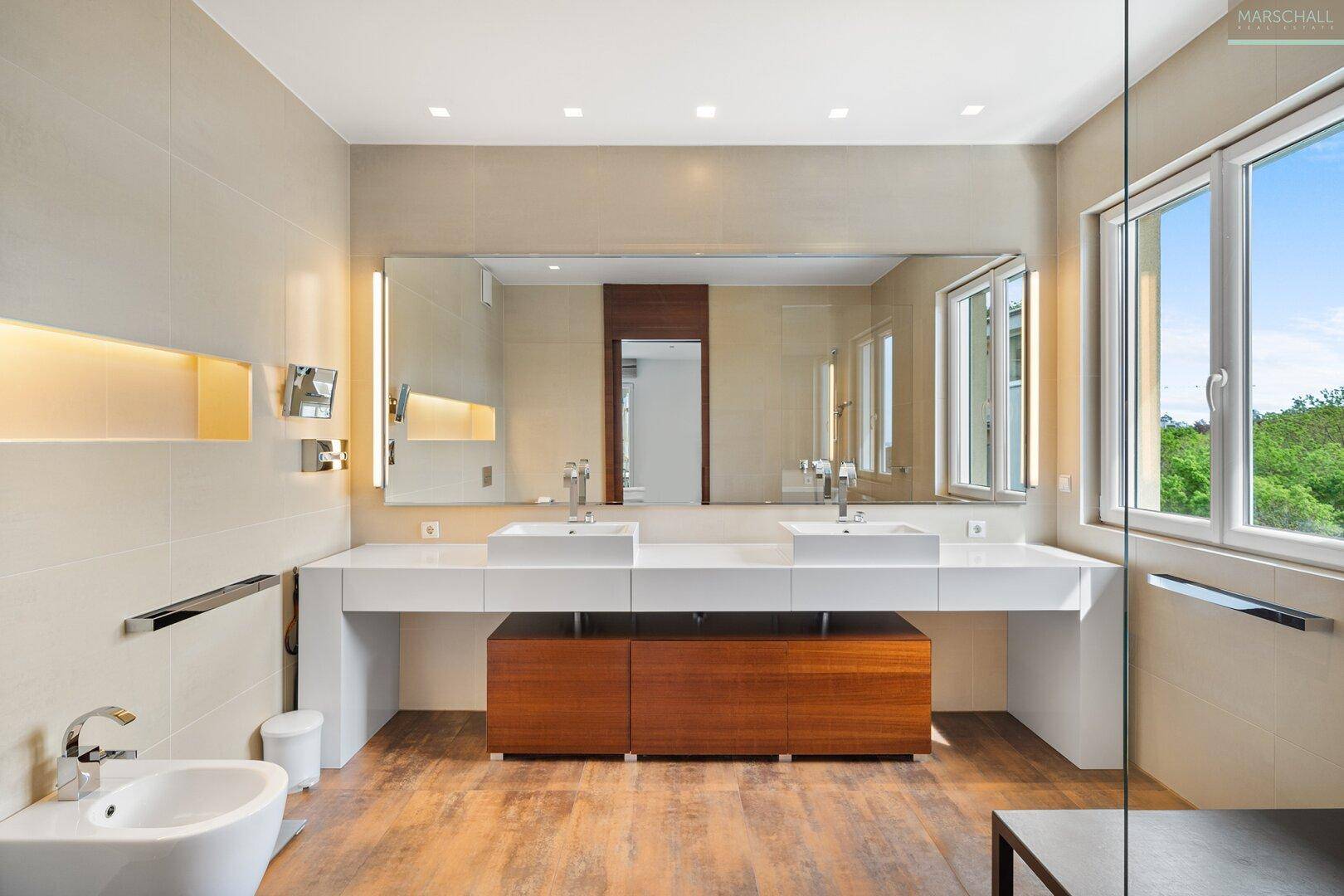 Modernes Badezimmer mit Doppelwaschbecken, großem Spiegel, Bidet und Fenster.