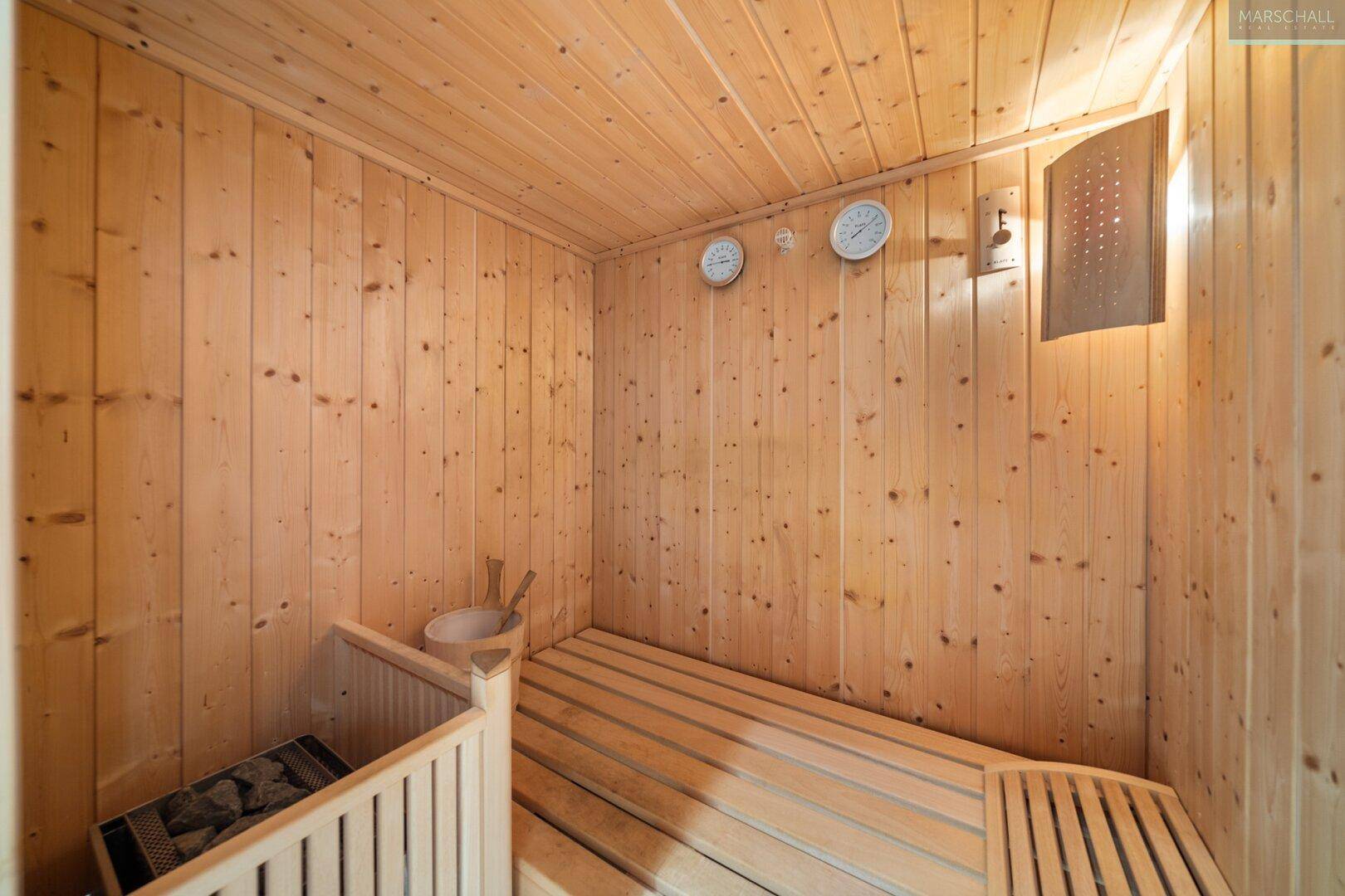 Gemütliche Holzsauna mit Bänken und traditionellem Saunaofen für Entspannung.