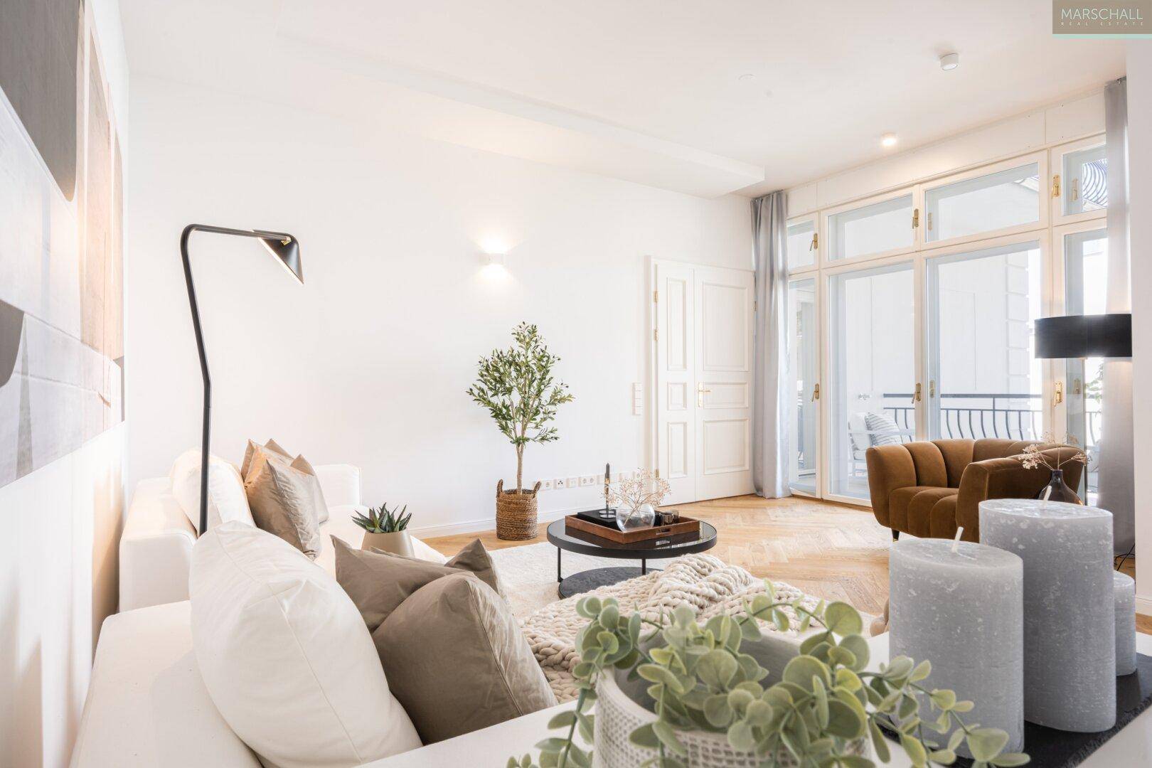 Lichtdurchflutetes Wohnzimmer mit bequemen Sofas, Holzboden und Zugang zu einem französischen Balkon.