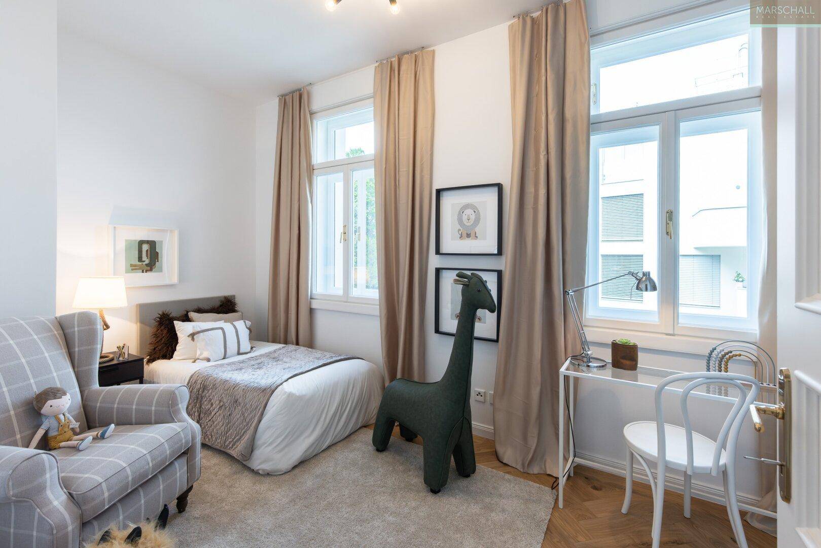 Helles Schlafzimmer mit Einzelbett, gemütlichem Sessel und großen Fenstern für viel Tageslicht.