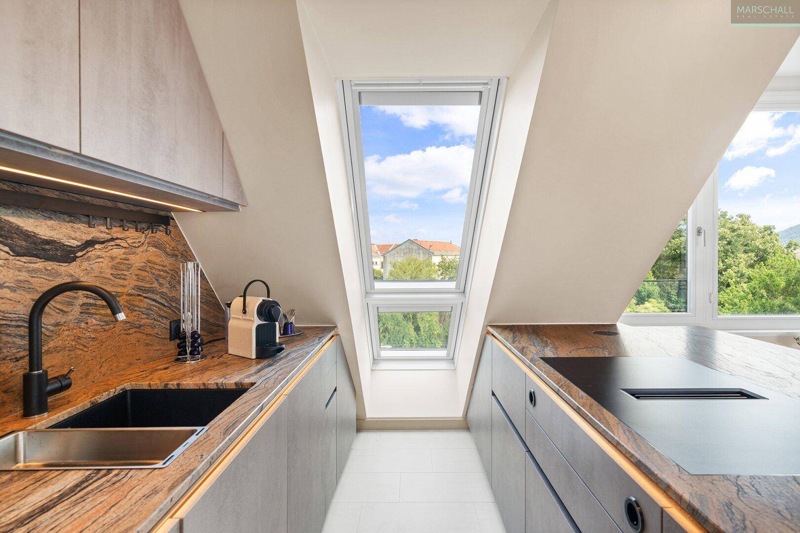 Helle Küche mit Dachfenster, Arbeitsflächen aus Naturstein und integriertem Spülbecken.