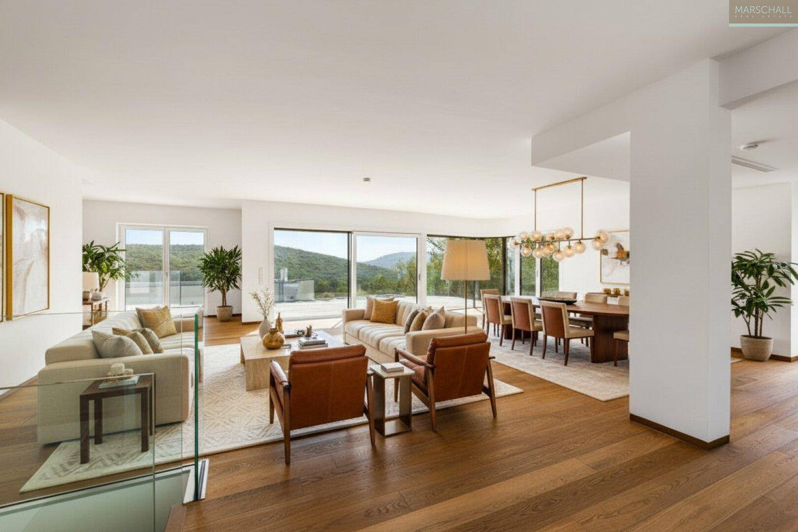 Helles, offenes Wohn-Esszimmer mit Holzboden, großen Fenstern und weitem Blick ins Grüne.
