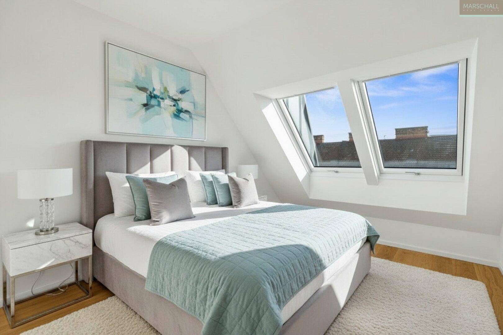 Helles Schlafzimmer mit Dachfenstern, Holzboden und modernem Bett, bietet eine angenehme Atmosphäre.