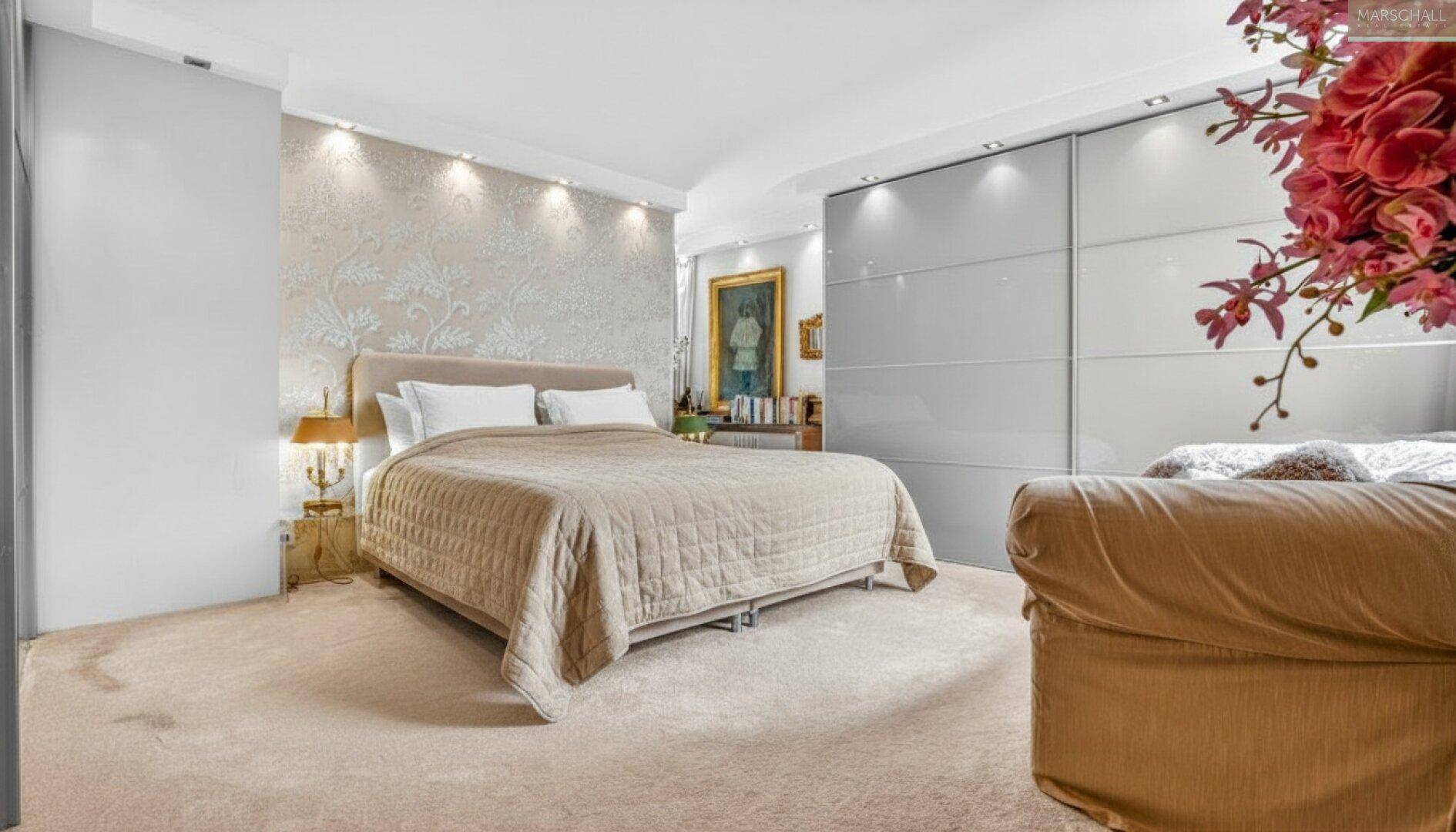 Ruhiges Schlafzimmer mit großem Bett, dekorativer Wandgestaltung und hellen Einbauschränken.