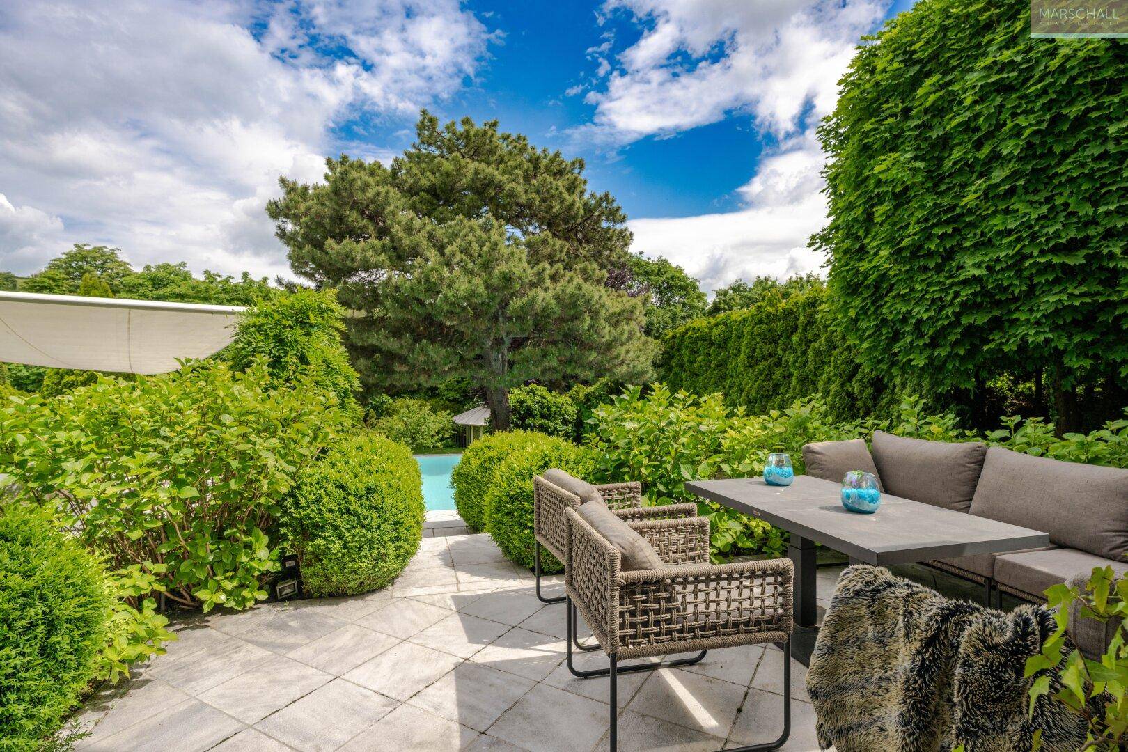 Gemütlicher Außenbereich auf einer Terrasse mit Sitzgelegenheiten und Blick auf den Pool.