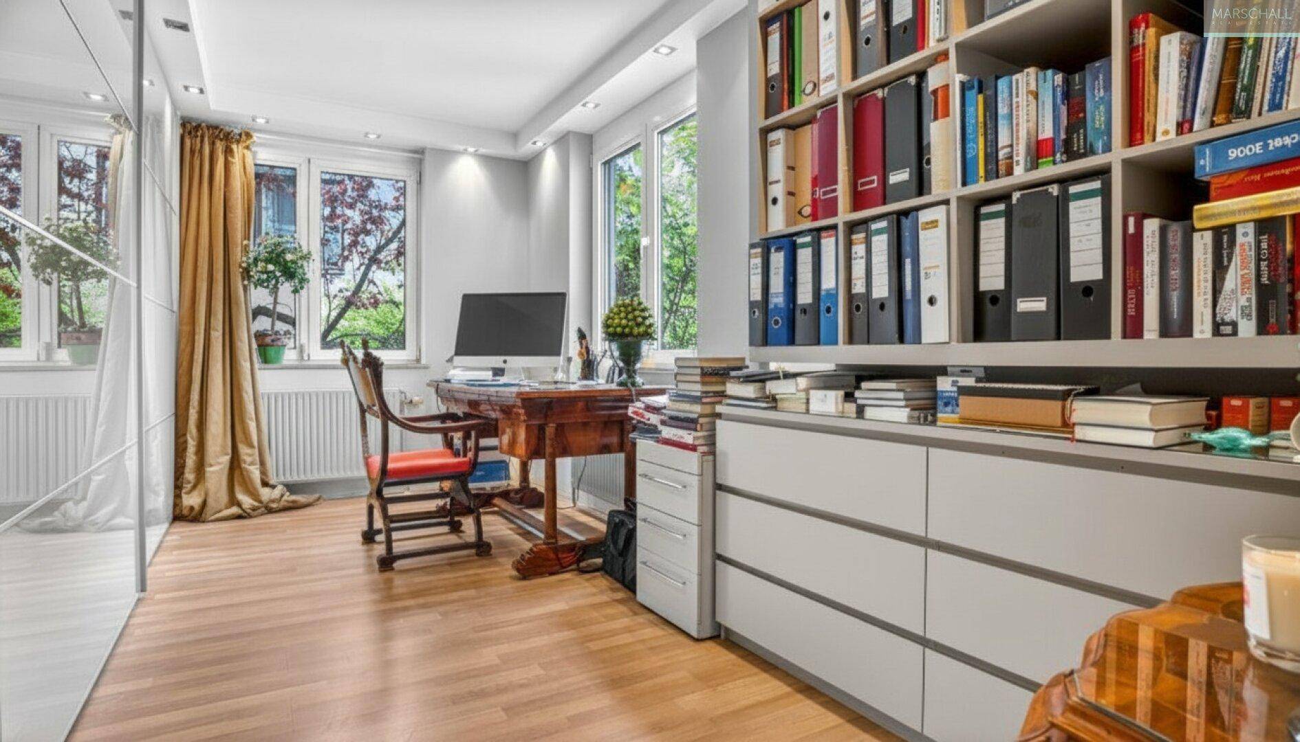 Helles Arbeitszimmer mit großem Bücherregal, Schreibtisch und elegantem Holzfußboden.