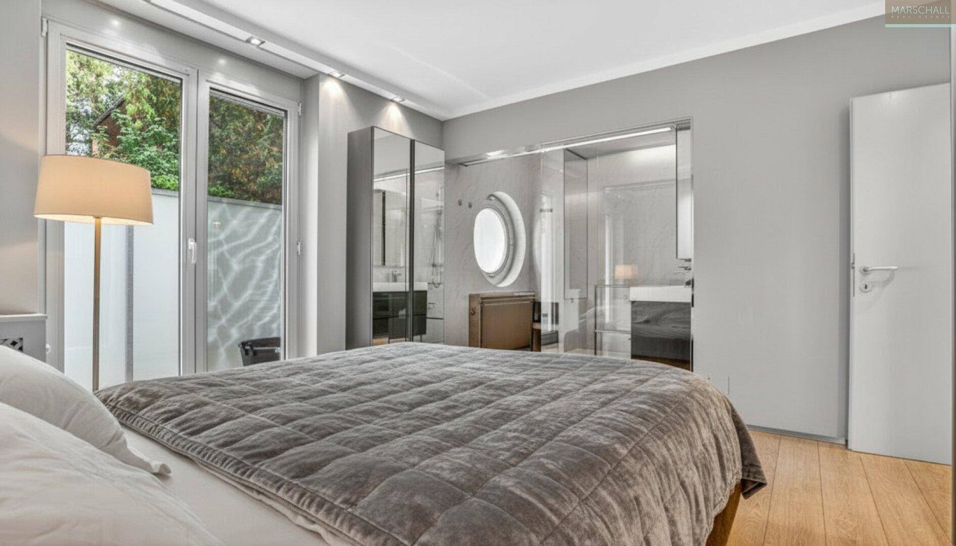 Helles Schlafzimmer mit großem Bett, Zugang zum Außenbereich und angrenzendem Badezimmer.