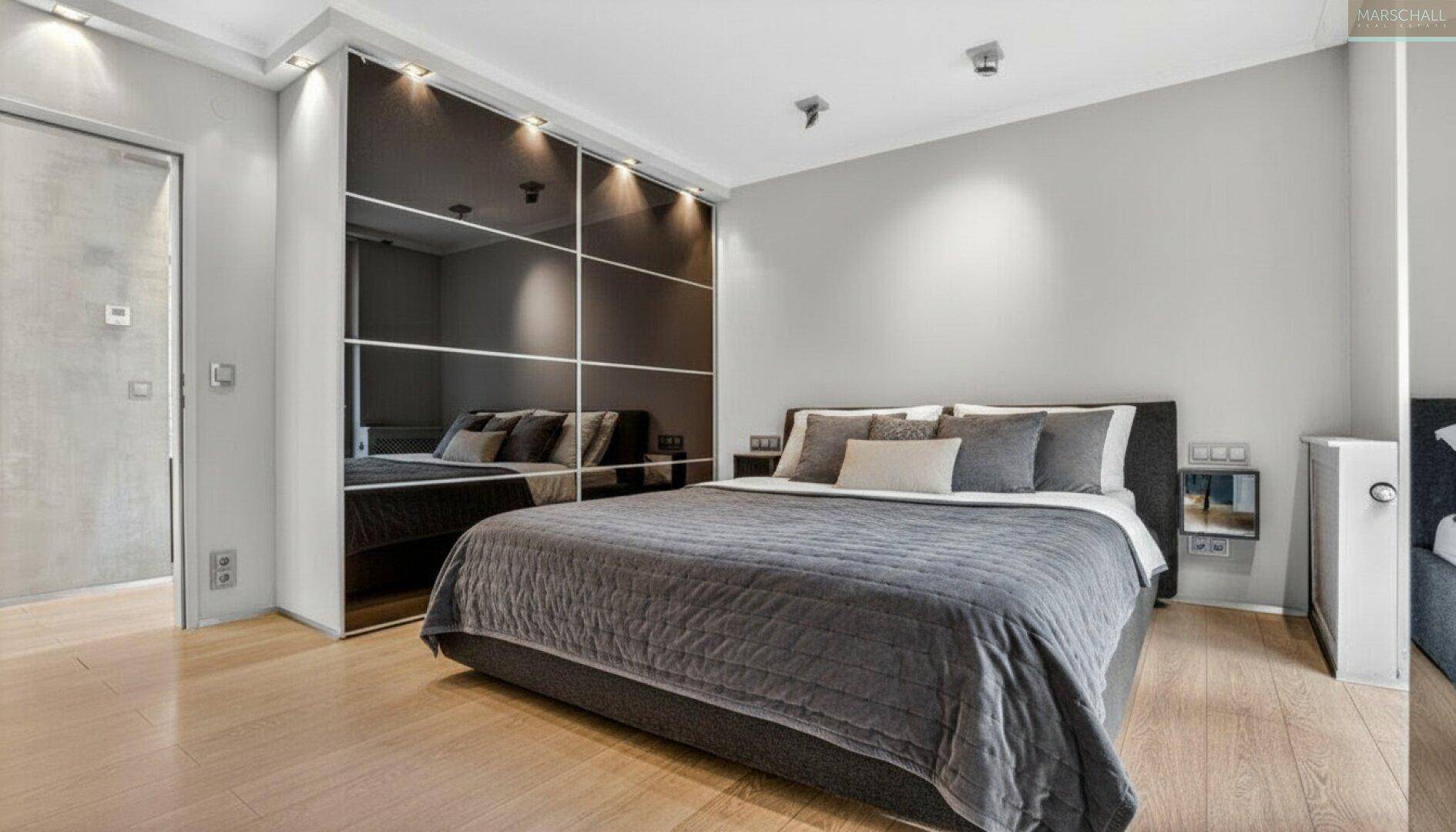 Modernes Schlafzimmer mit großem Bett und elegantem Spiegelschrank, der den Raum erweitert.